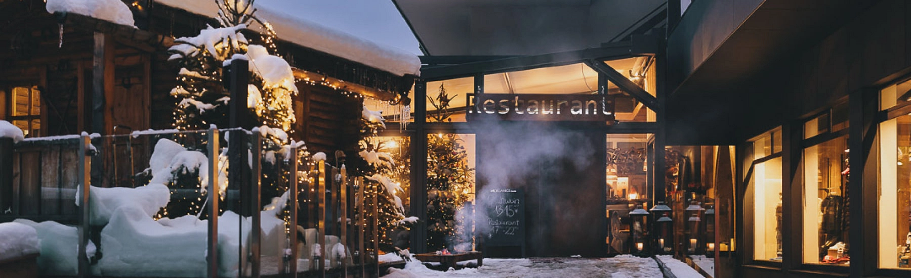 Eingang eines Restaurants mit festlichen Lichtern im Schnee