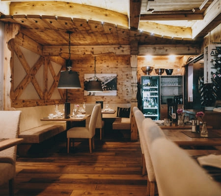 Gemütliches Restaurant mit Holzwänden, Tischen und LED-Beleuchtung.