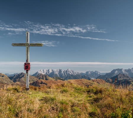 Kreuz auf einem Hügel mit Bergpanorama im Hintergrund