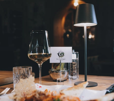 Tischgedeck im Restaurant Der Gollinger mit Wein und Lampenlicht