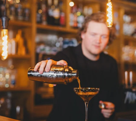 Bartender gießt einen Cocktail in ein Glas.