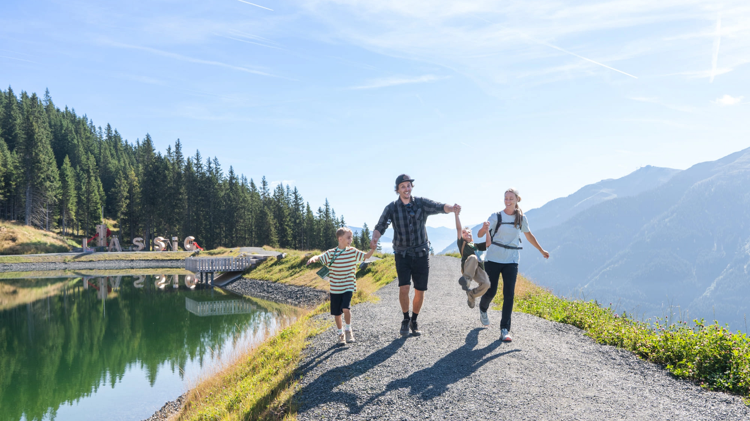 Family hiking along a path by a lake at Reiterkogel.